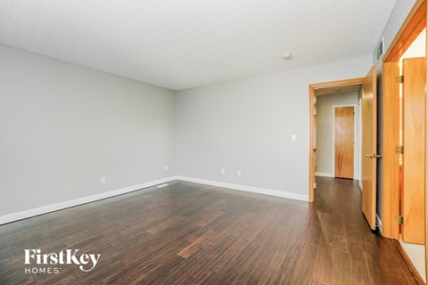 a living room with wood floors and a door to a hallway