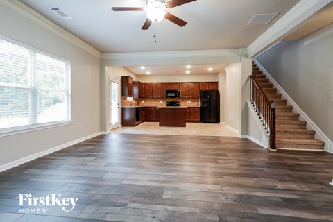 an empty living room with a staircase and a kitchen