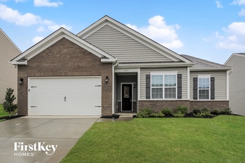 a brick house with a white garage door in front of a green lawn