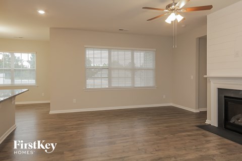 an empty living room with a fireplace and a ceiling fan