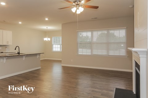 an empty living room and kitchen with a ceiling fan