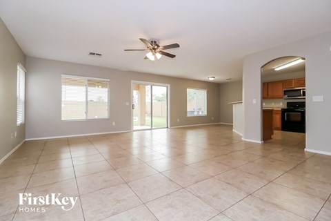 an empty living room with tile flooring and a ceiling fan