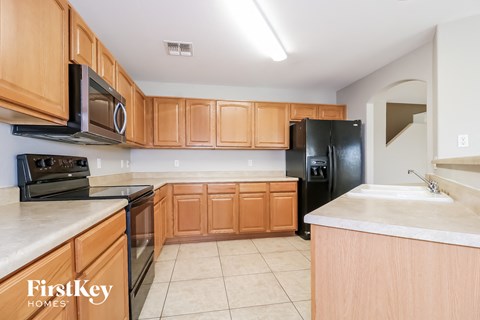 an empty kitchen with wooden cabinets and black appliances
