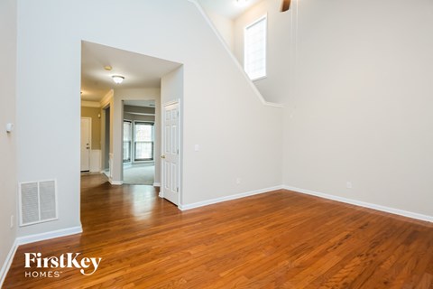A room with wooden floors and white walls, with a staircase leading to another room.