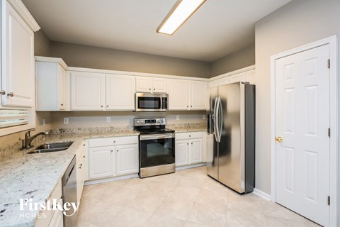 A kitchen with a refrigerator, sink, and cabinets.