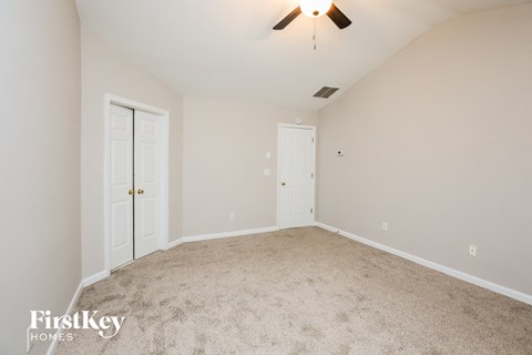 A spacious room with a carpeted floor and a ceiling fan.