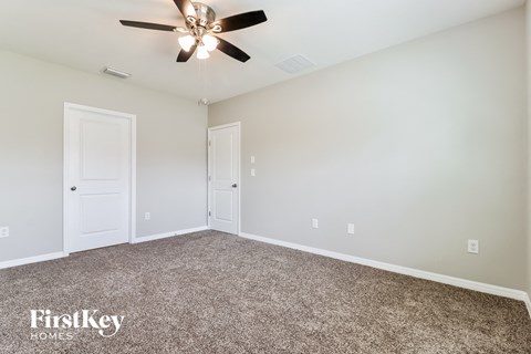 the spacious living room with ceiling fan and carpet