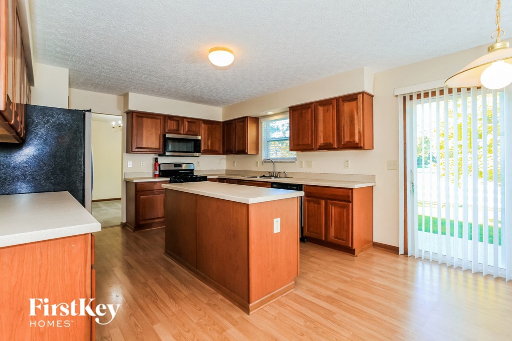 a kitchen with wooden cabinets and a large window