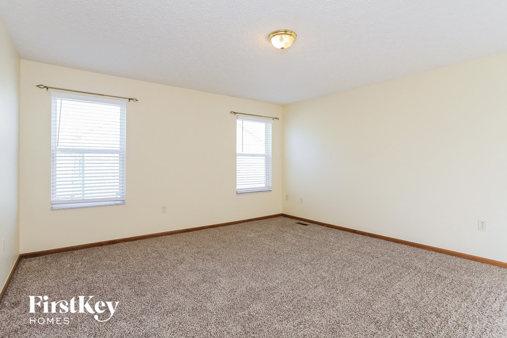 the living room of an empty house with carpet and two windows