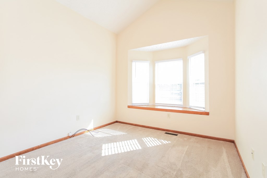 an empty room with a window and a carpet