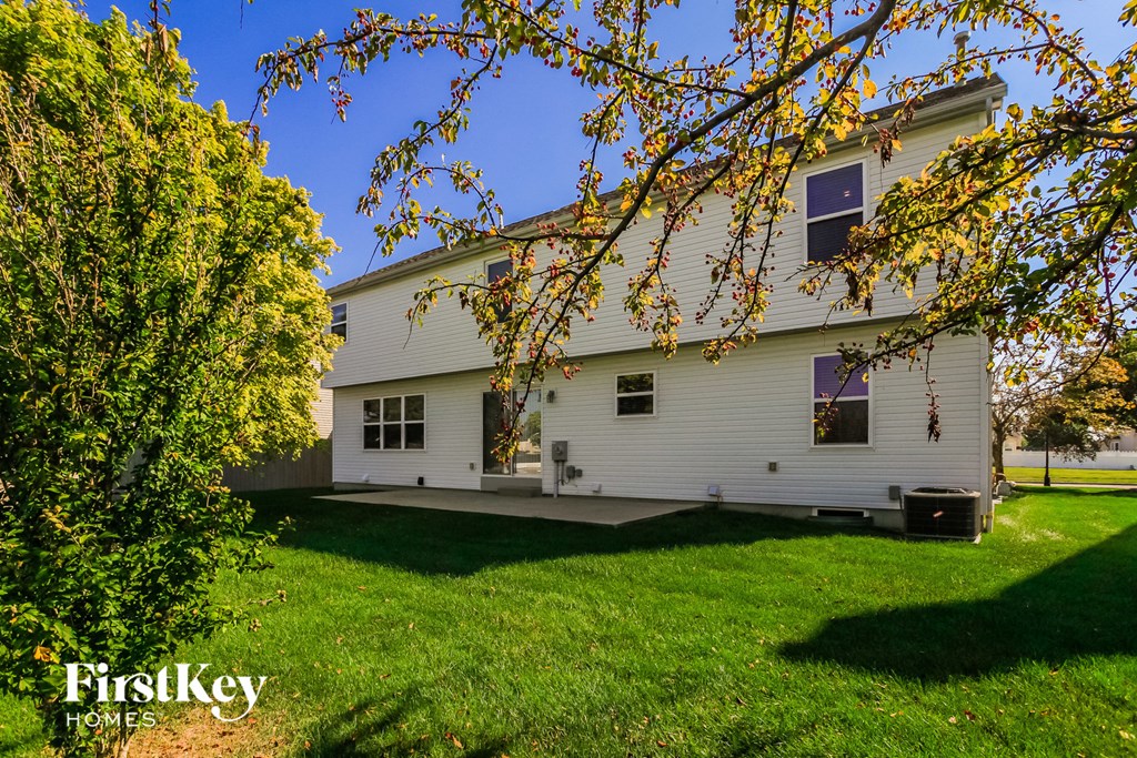 a white house with a green lawn and a tree