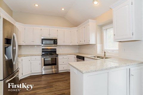 A kitchen with white cabinets and a marble countertop.