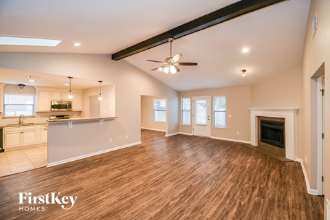 A spacious living room with wooden floors and a fireplace.