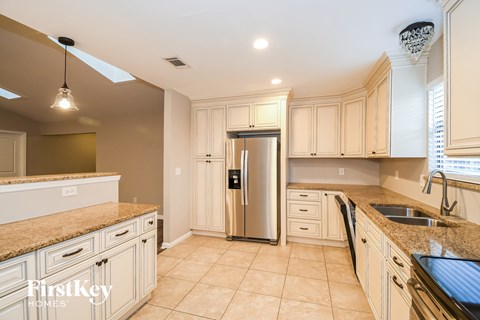 A kitchen with a refrigerator, sink, and cabinets.