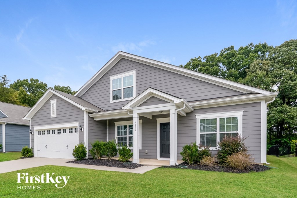 a gray house with a white garage door and a lawn