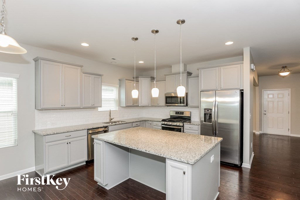 a kitchen with white cabinets and a marble counter top