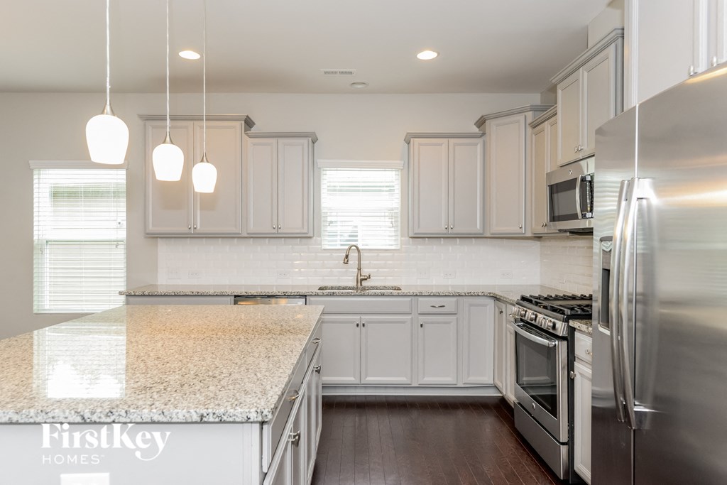 a white kitchen with marble counter tops and stainless steel appliances