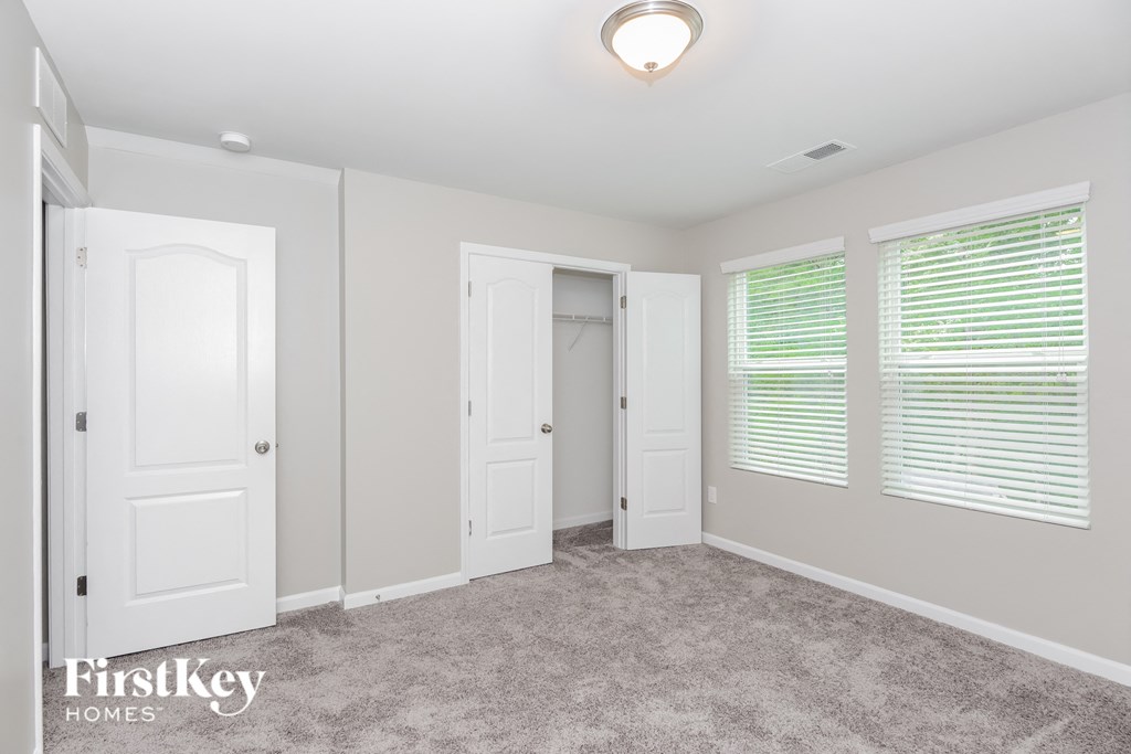 a bedroom with three doors and a carpeted floor and a closet