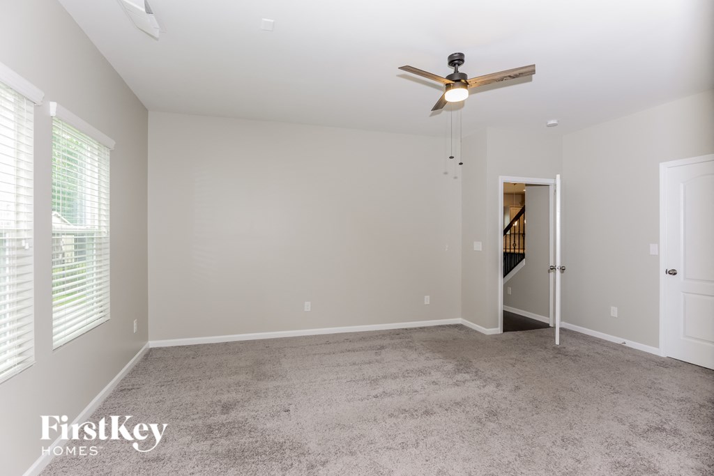a spacious living room with carpet and a ceiling fan