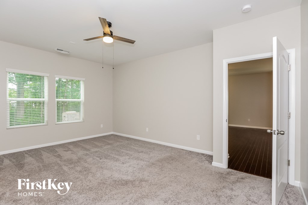 a empty living room with a ceiling fan and a door to a closet