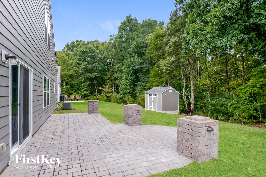 a backyard with a brick path and a shed on the side of a house