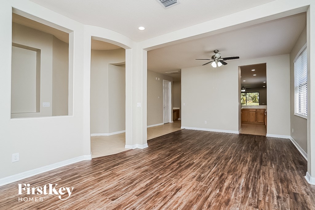 A spacious room with wooden floors and a ceiling fan.