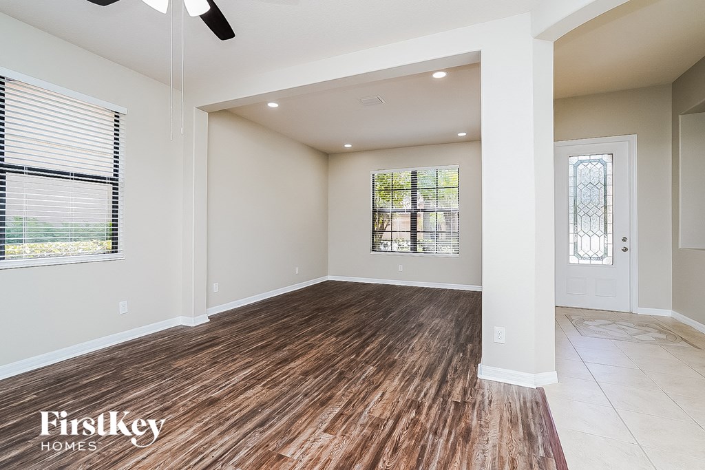 A spacious room with wooden flooring and a ceiling fan.