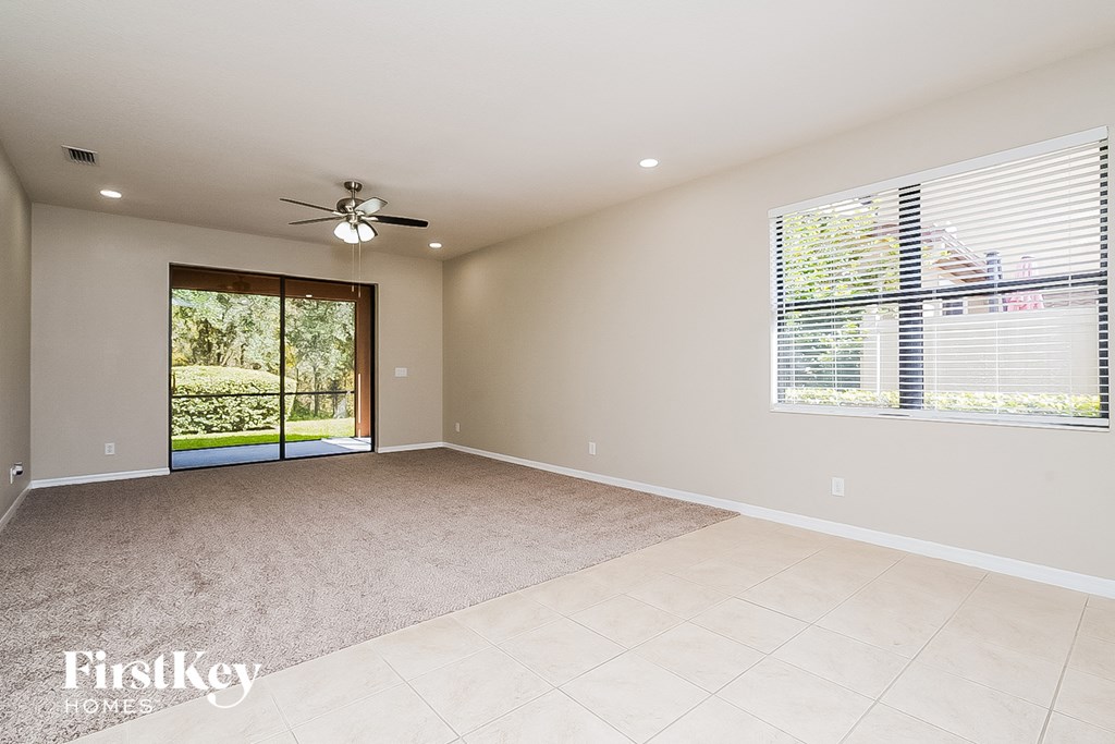 A spacious room with a ceiling fan and a large window with blinds.