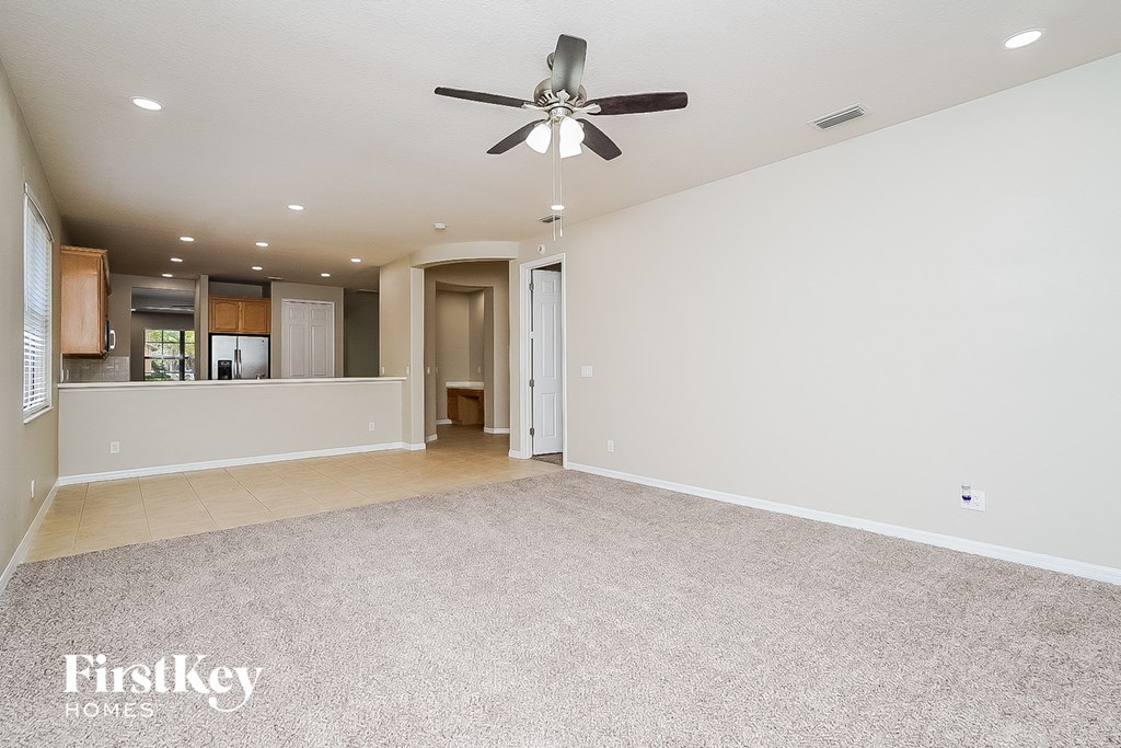 A spacious room with a ceiling fan and carpeted floor.