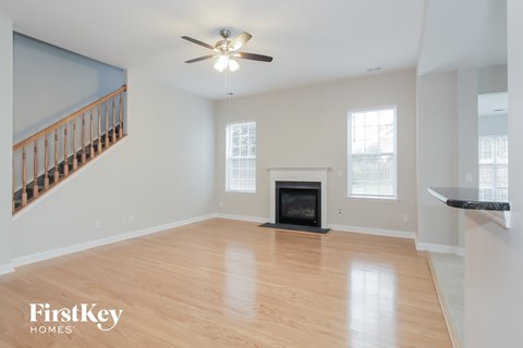 an empty living room with a fireplace and a ceiling fan