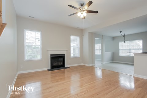 an empty living room with a fireplace and a ceiling fan