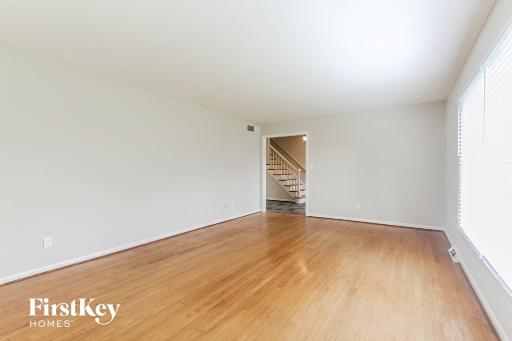 a spacious living room with wood floors and white walls