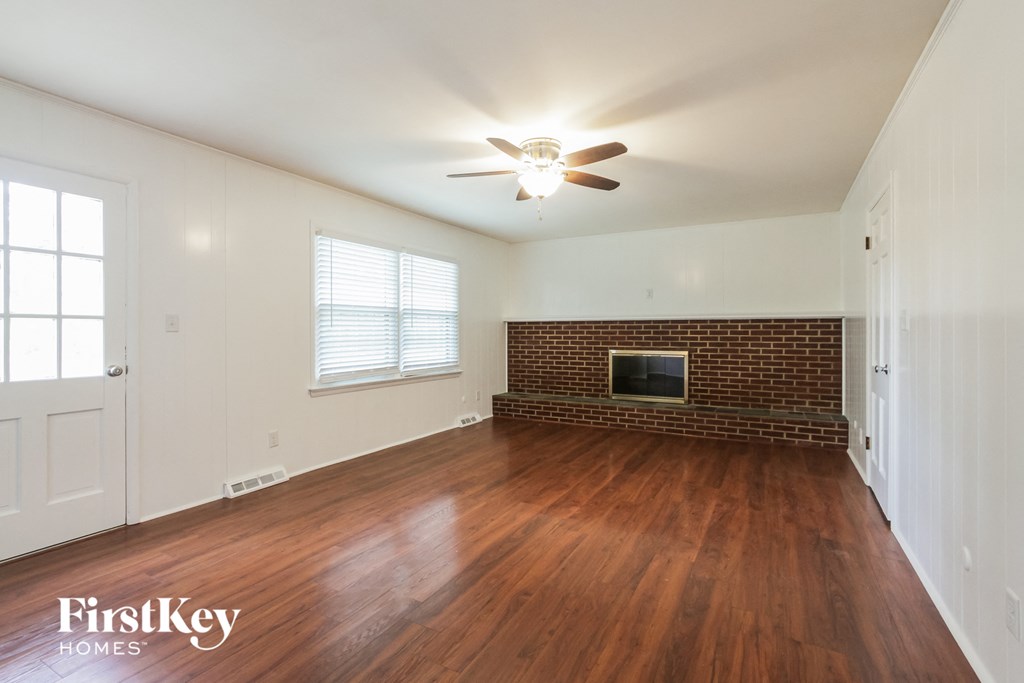 an empty living room with a ceiling fan and a fireplace