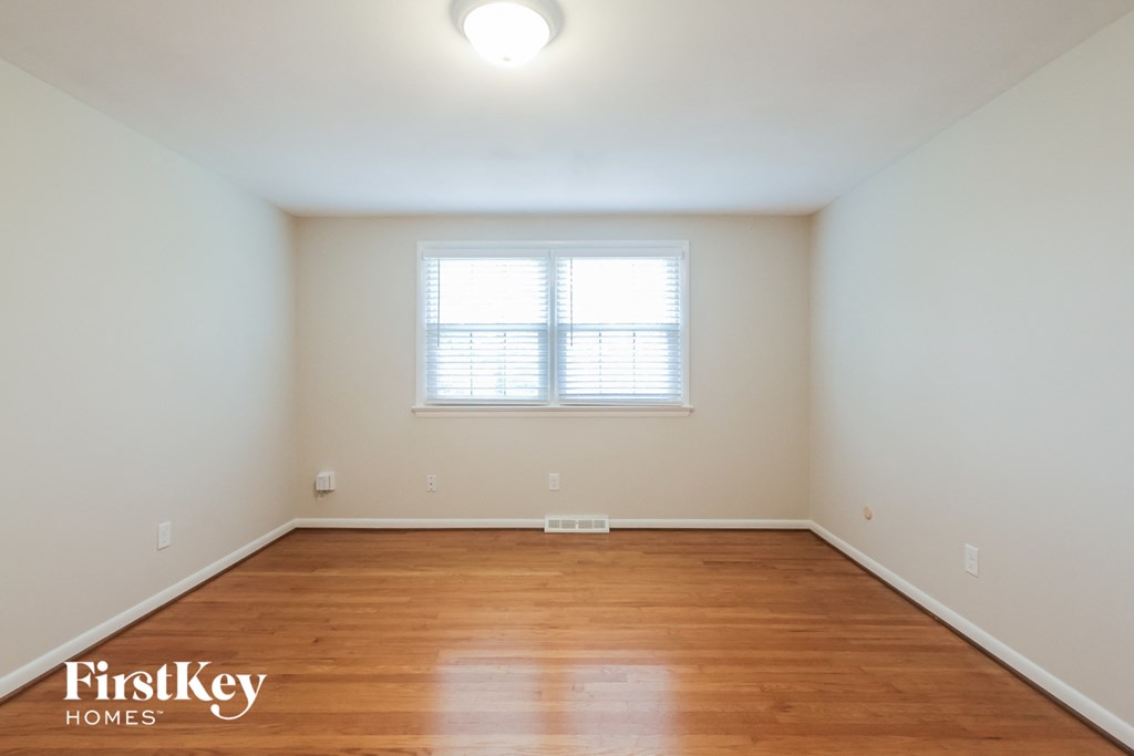 the spacious living room with hardwood flooring and a window