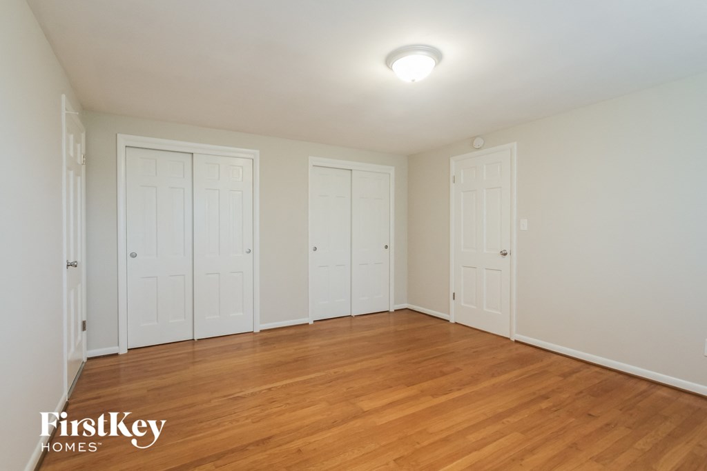 the living room of a house with white doors and a wood floor