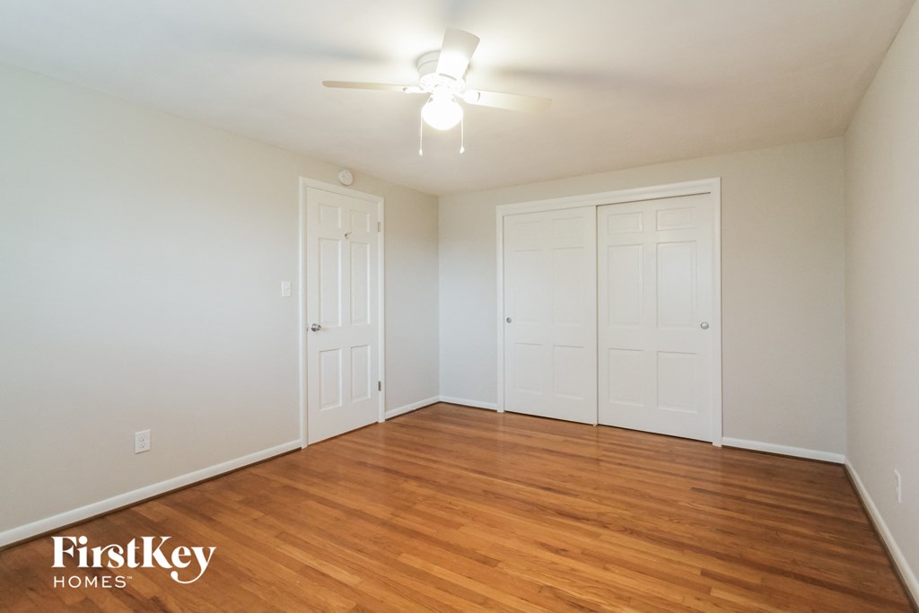 a bedroom with wood flooring and a ceiling fan