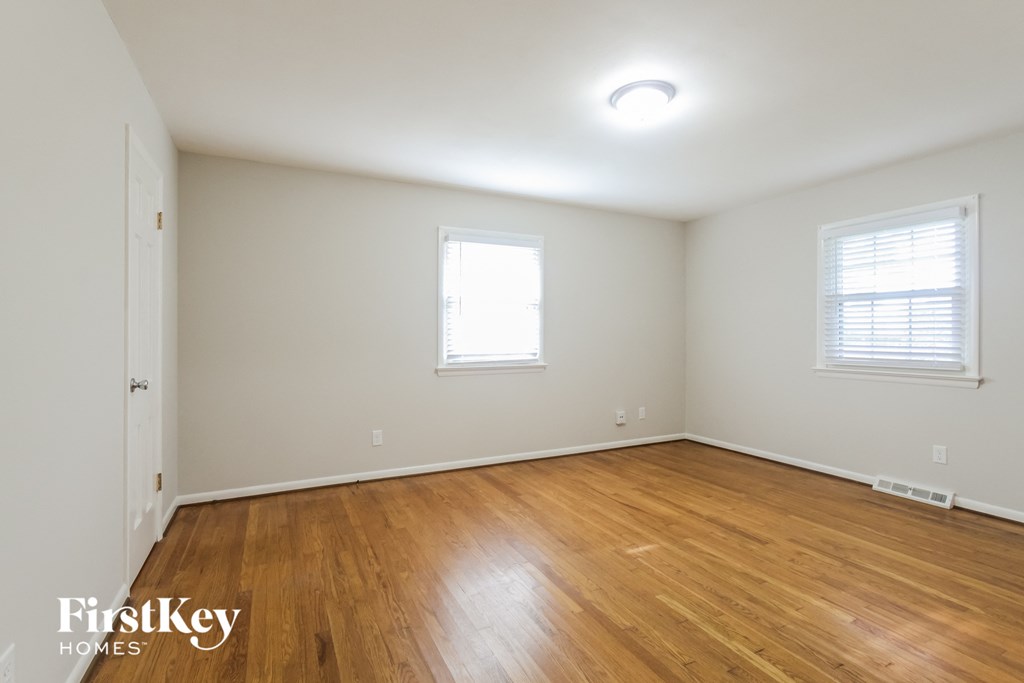 the living room of a home with wooden floors and white walls