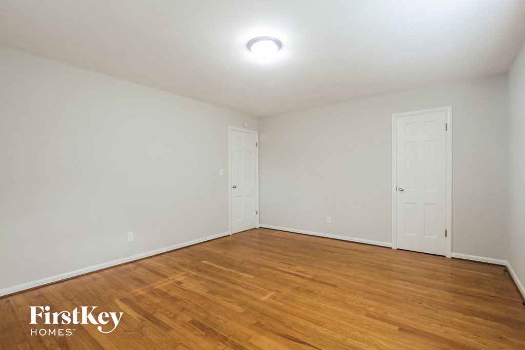the spacious living room with wood flooring and white walls