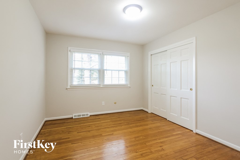 a bedroom with a wooden floor and a white door and a window