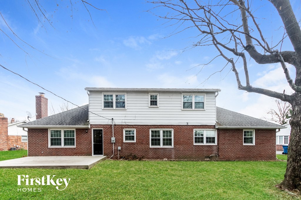 front view of a brick house with white siding and green grass