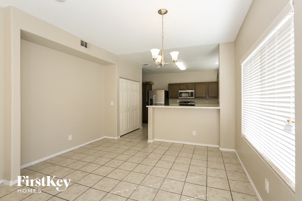A spacious room with a kitchenette in the background.