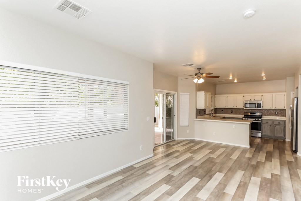 an empty living room with a kitchen in the background