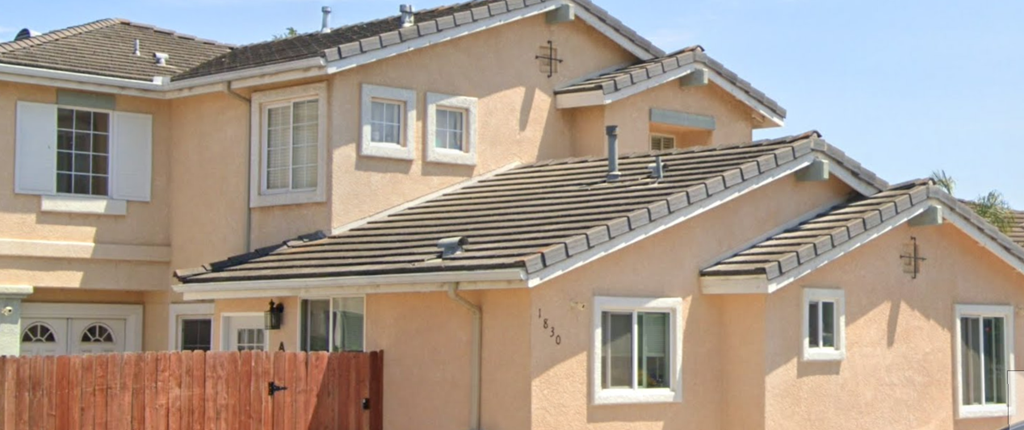 A two-story house with a brown fence in front.