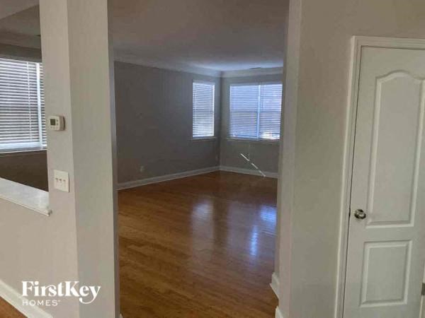 A room with wooden floors and white walls, with a door on the right side.