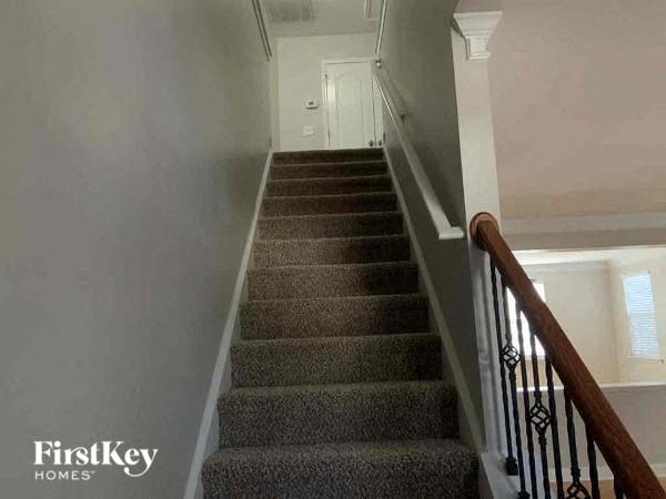 A staircase with a carpeted runner and a wooden handrail.