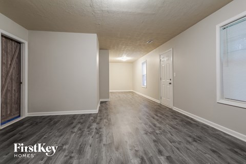 A spacious room with wooden flooring and white walls, branded with "FirstKey Homes".