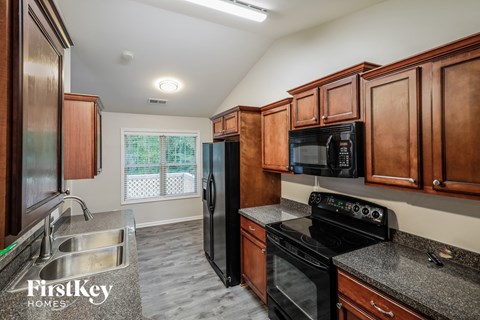 A kitchen with wooden cabinets and black appliances.