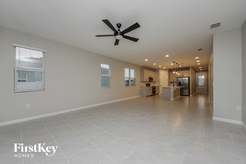 a spacious living room with tile flooring and a ceiling fan