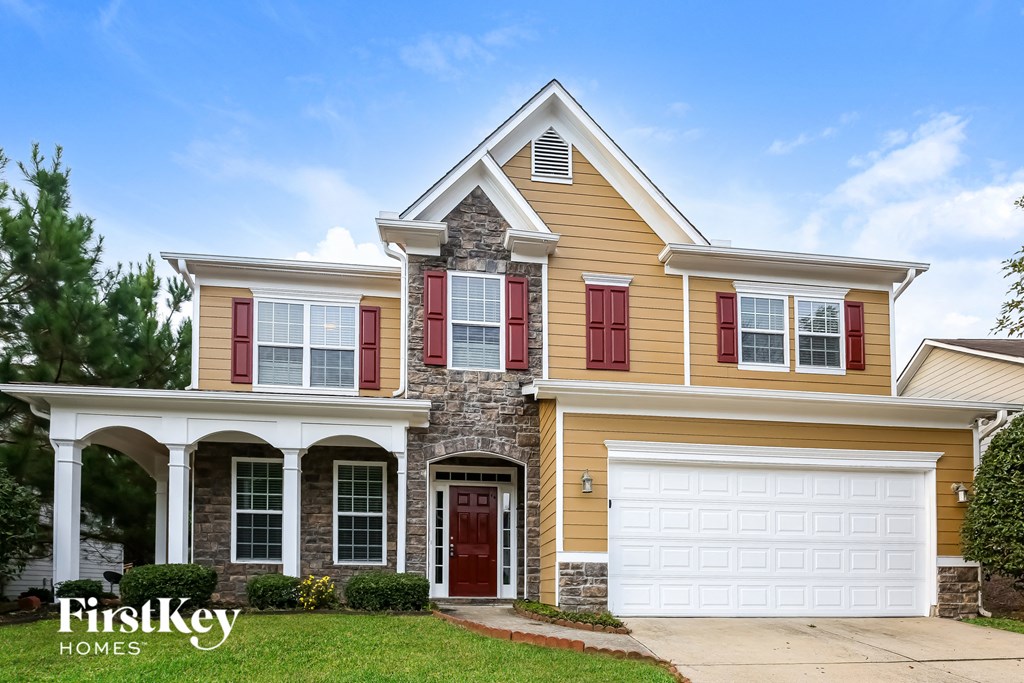 A two-story house with a garage and a stone pillar.