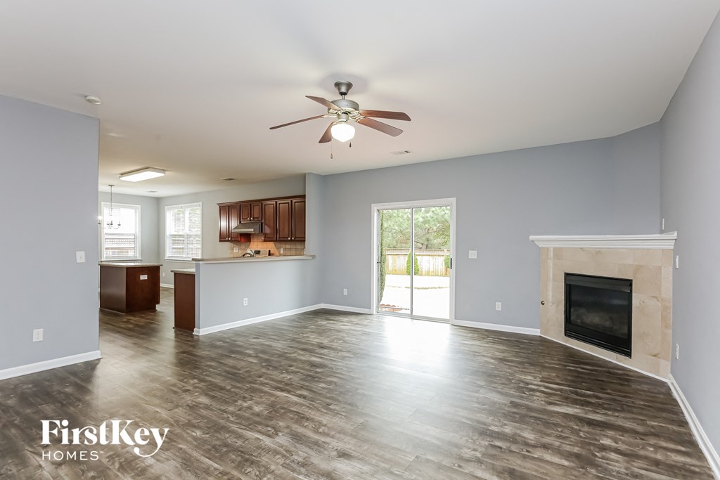 A spacious living room with a fireplace and a ceiling fan.